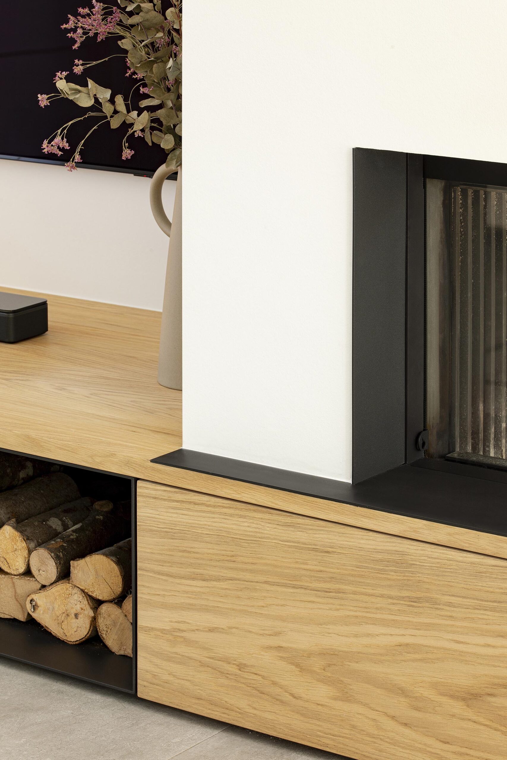 Séjour contemporain avec meuble sur mesure intégrant le foyer et la télévision, chêne clair et accents noirs, dans une ambiance chaleureuse et raffinée