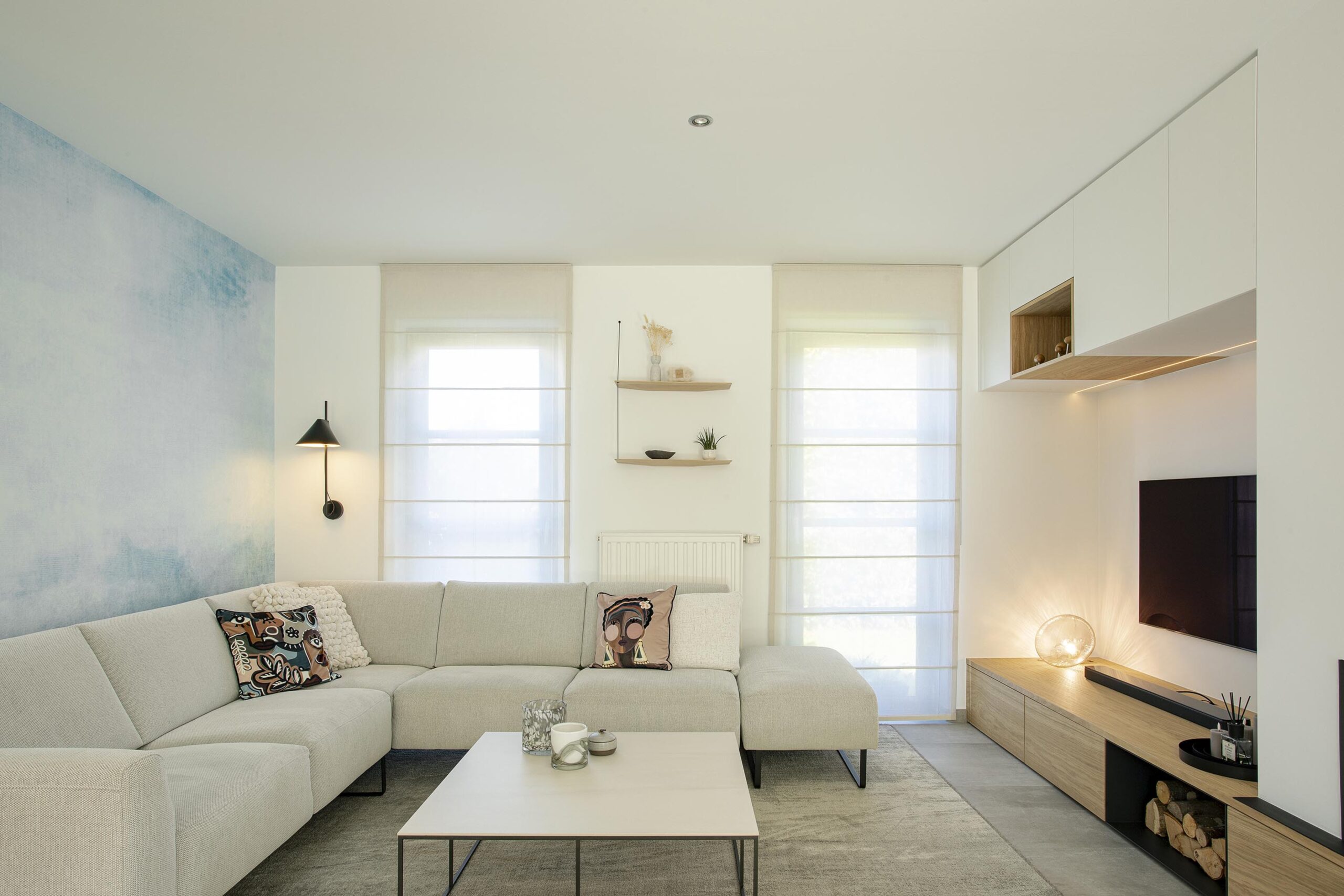 Séjour contemporain avec meuble sur mesure intégrant le foyer et la télévision, chêne clair et accents noirs, dans une ambiance chaleureuse et raffinée