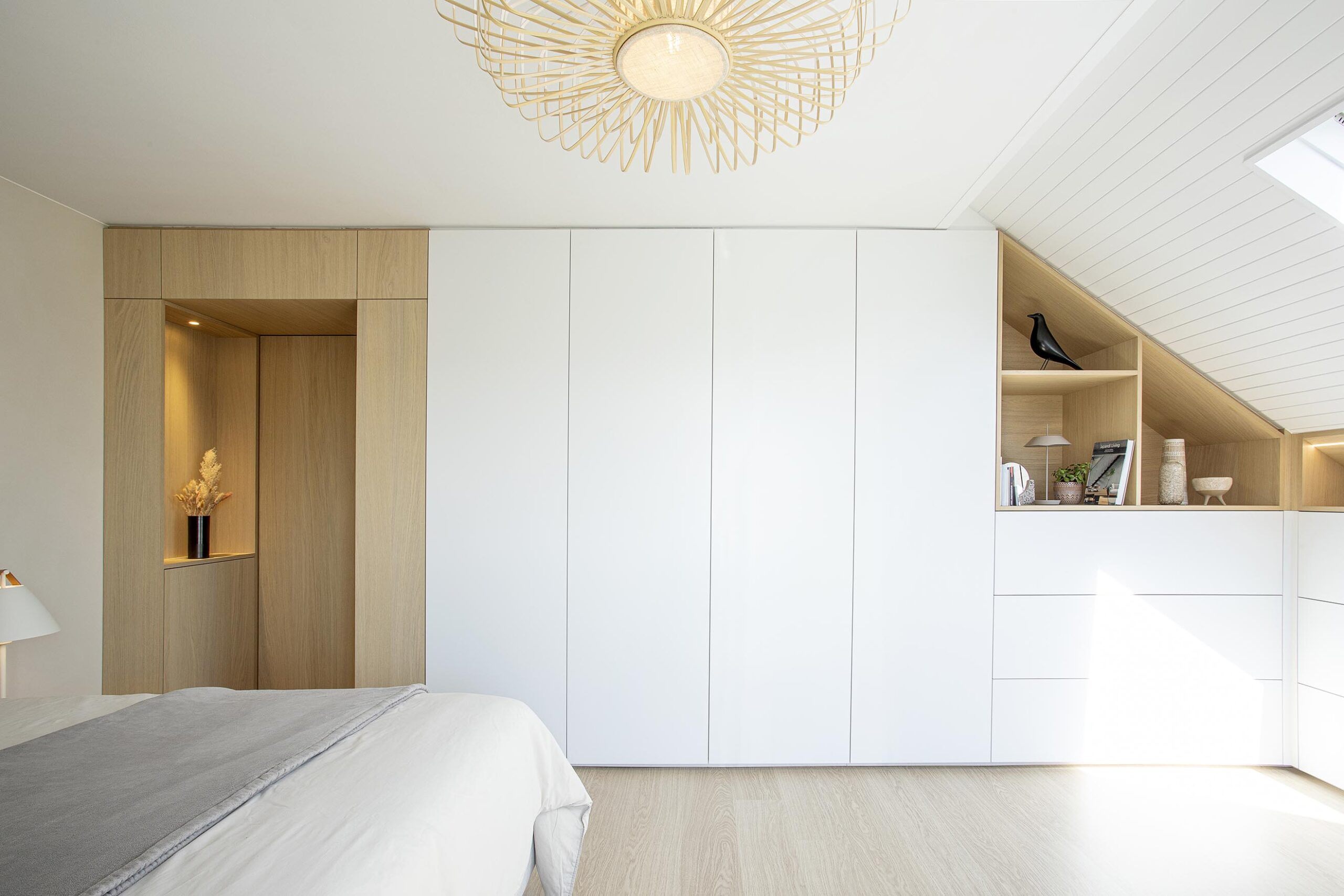 Chambre parentale contemporaine aux tons doux, avec murs à texture minérale, mobilier sur mesure en chêne clair et laque blanche, dans une atmosphère chaleureuse et apaisante
