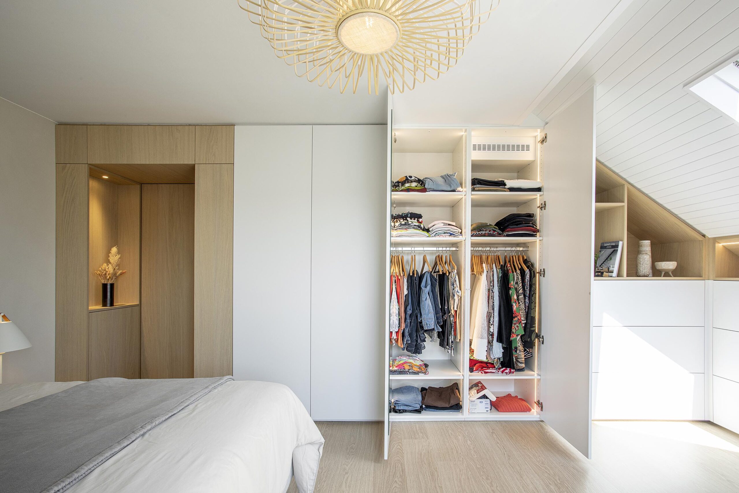 Chambre parentale contemporaine aux tons doux, avec murs à texture minérale, mobilier sur mesure en chêne clair et laque blanche, dans une atmosphère chaleureuse et apaisante