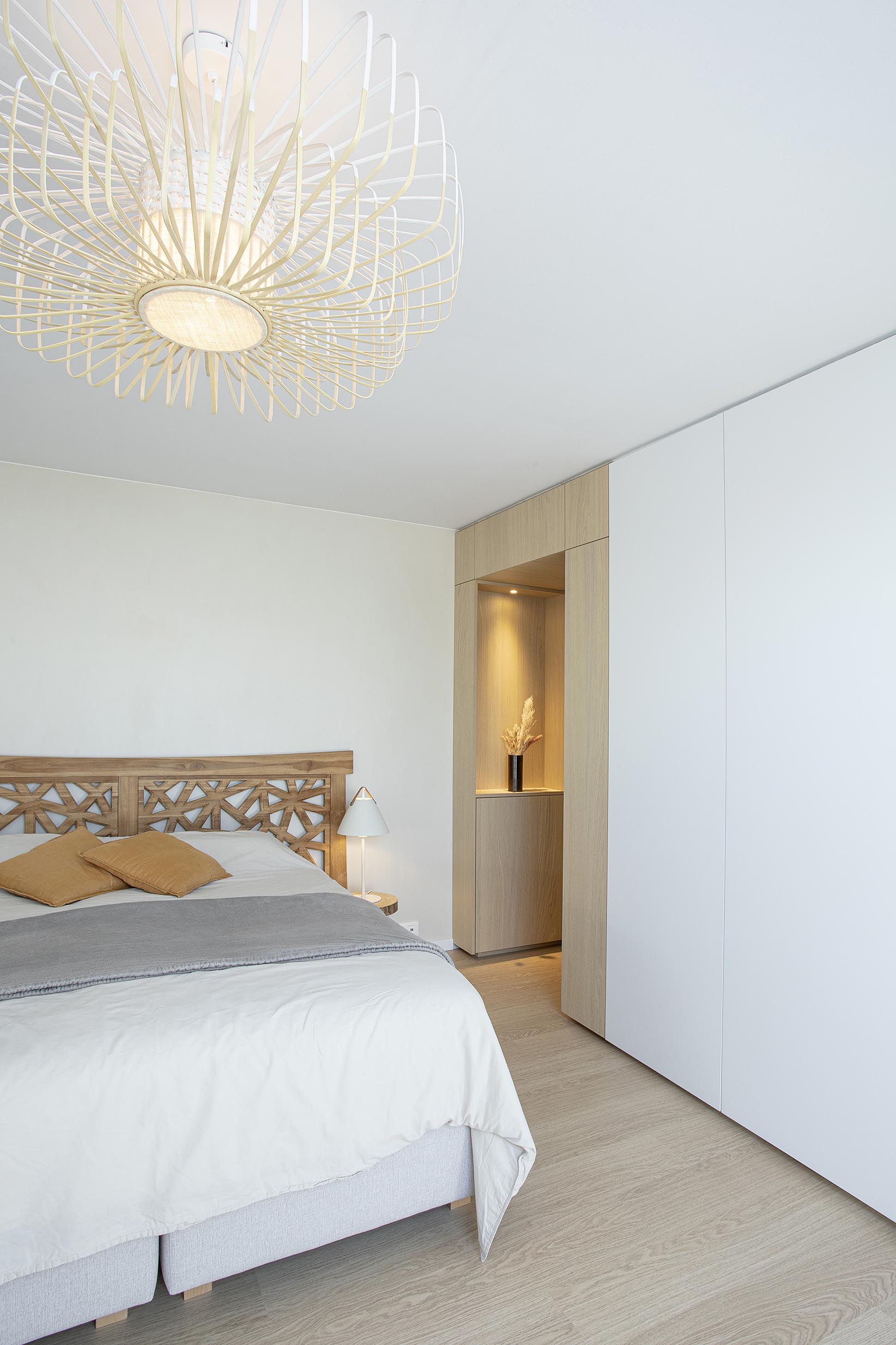 Chambre parentale contemporaine aux tons doux, avec murs à texture minérale, mobilier sur mesure en chêne clair et laque blanche, dans une atmosphère chaleureuse et apaisante