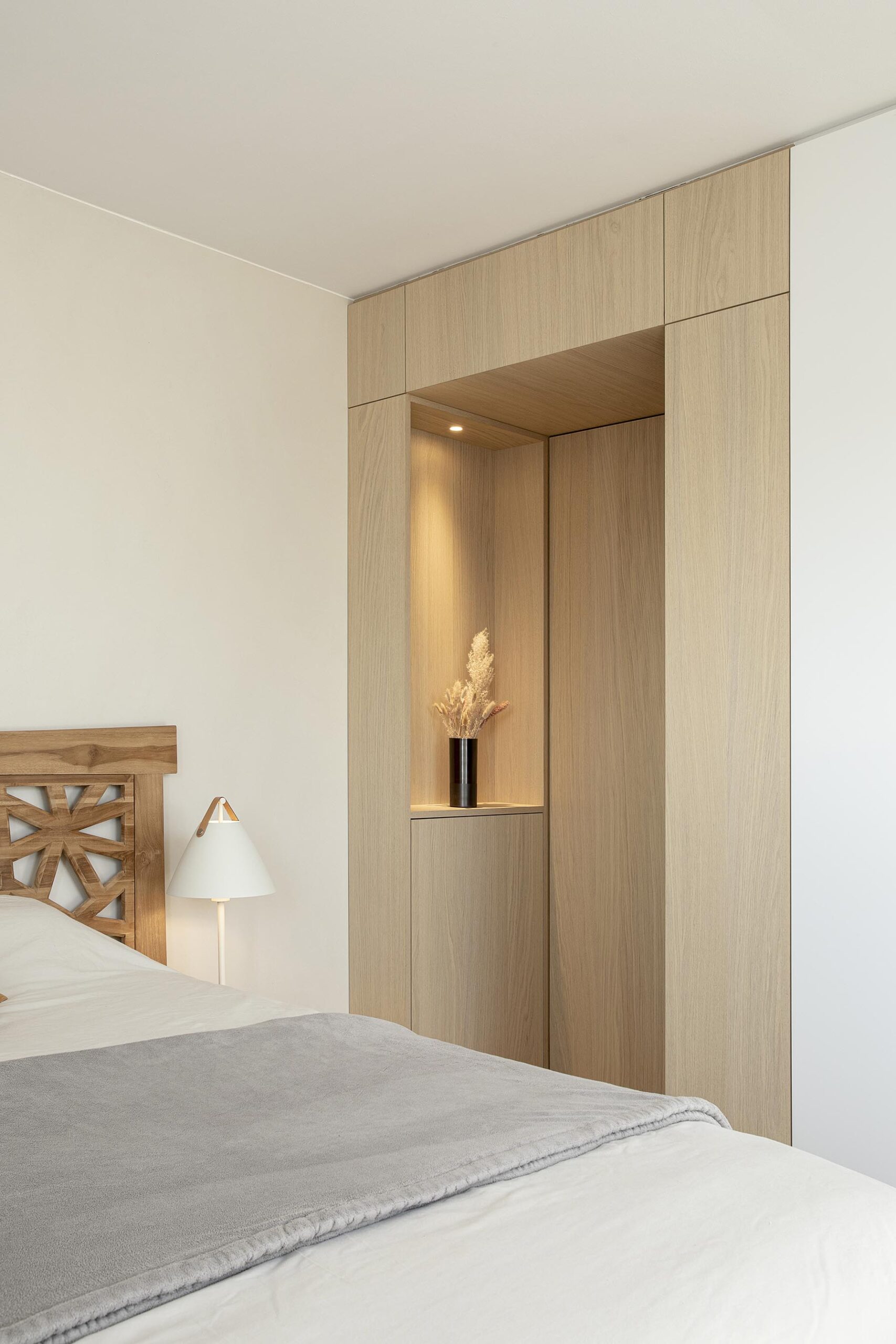 Chambre parentale contemporaine aux tons doux, avec murs à texture minérale, mobilier sur mesure en chêne clair et laque blanche, dans une atmosphère chaleureuse et apaisante