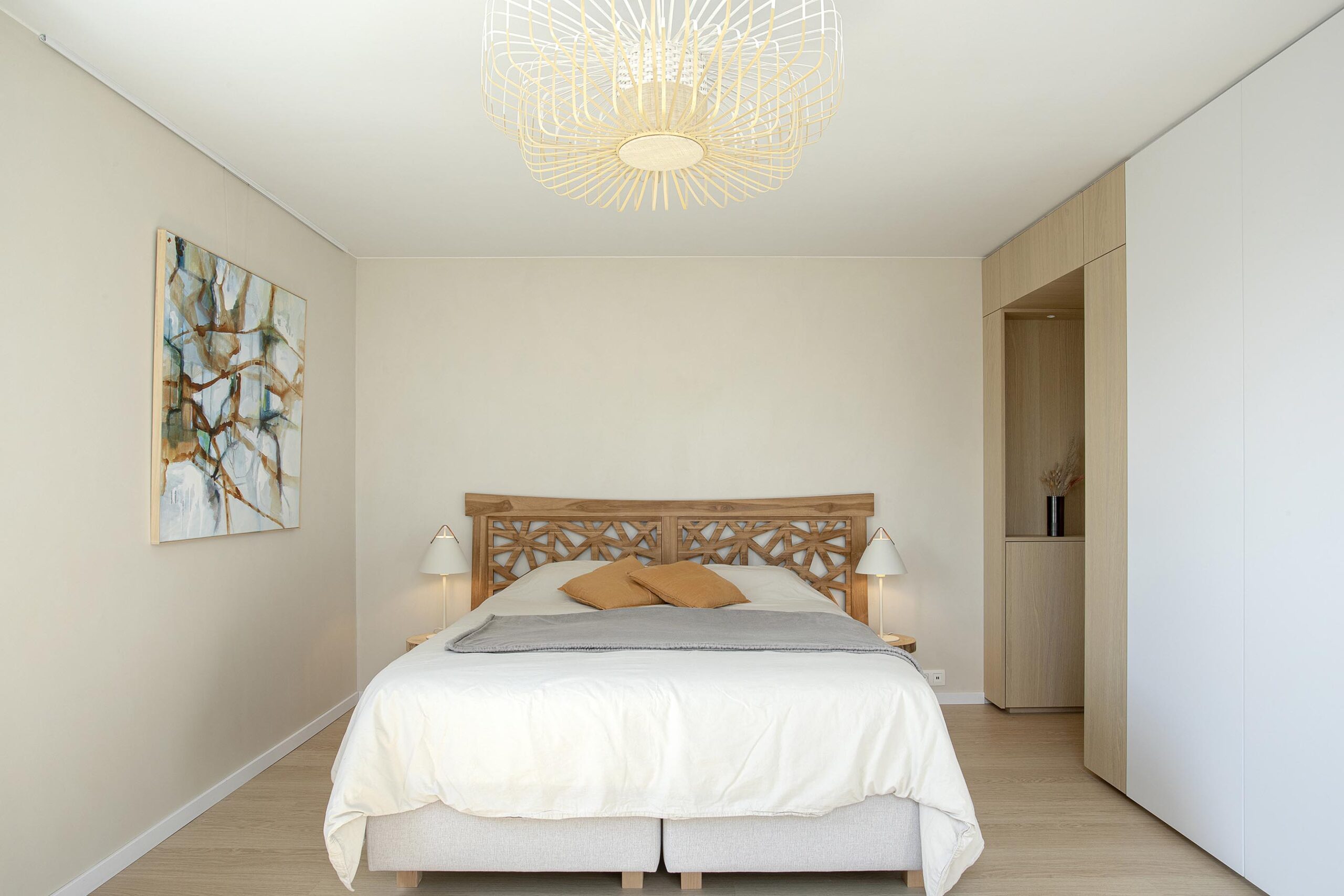 Chambre parentale contemporaine aux tons doux, avec murs à texture minérale, mobilier sur mesure en chêne clair et laque blanche, dans une atmosphère chaleureuse et apaisante