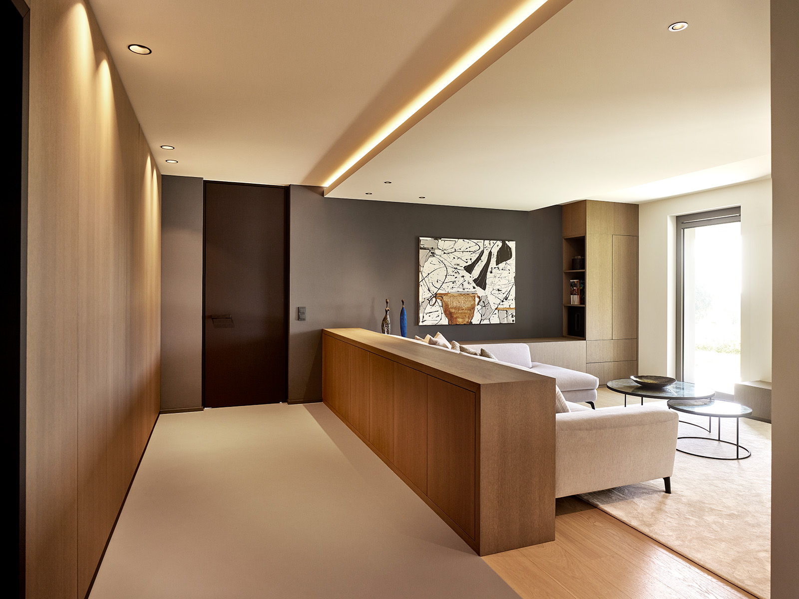 Salon contemporain haut de gamme avec mobilier sur mesure en bois, éclairage indirect et palette de tons neutres