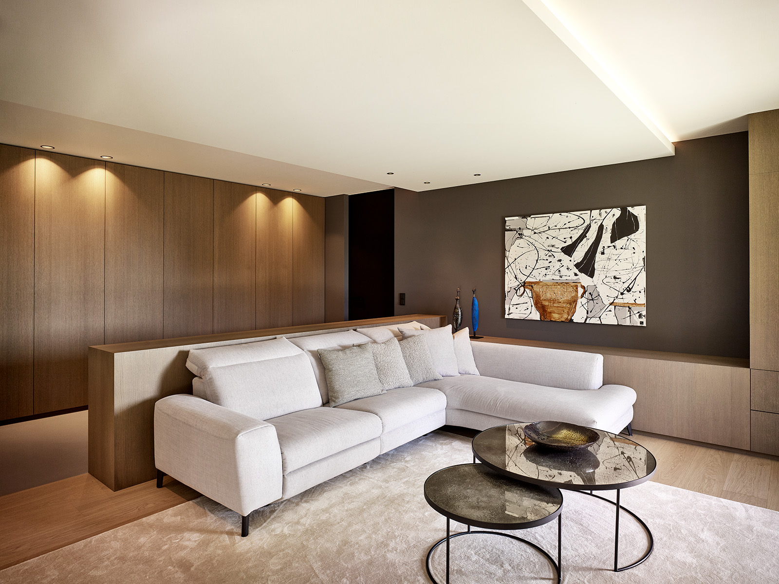 Salon contemporain haut de gamme avec mobilier sur mesure en bois, éclairage indirect et palette de tons neutre