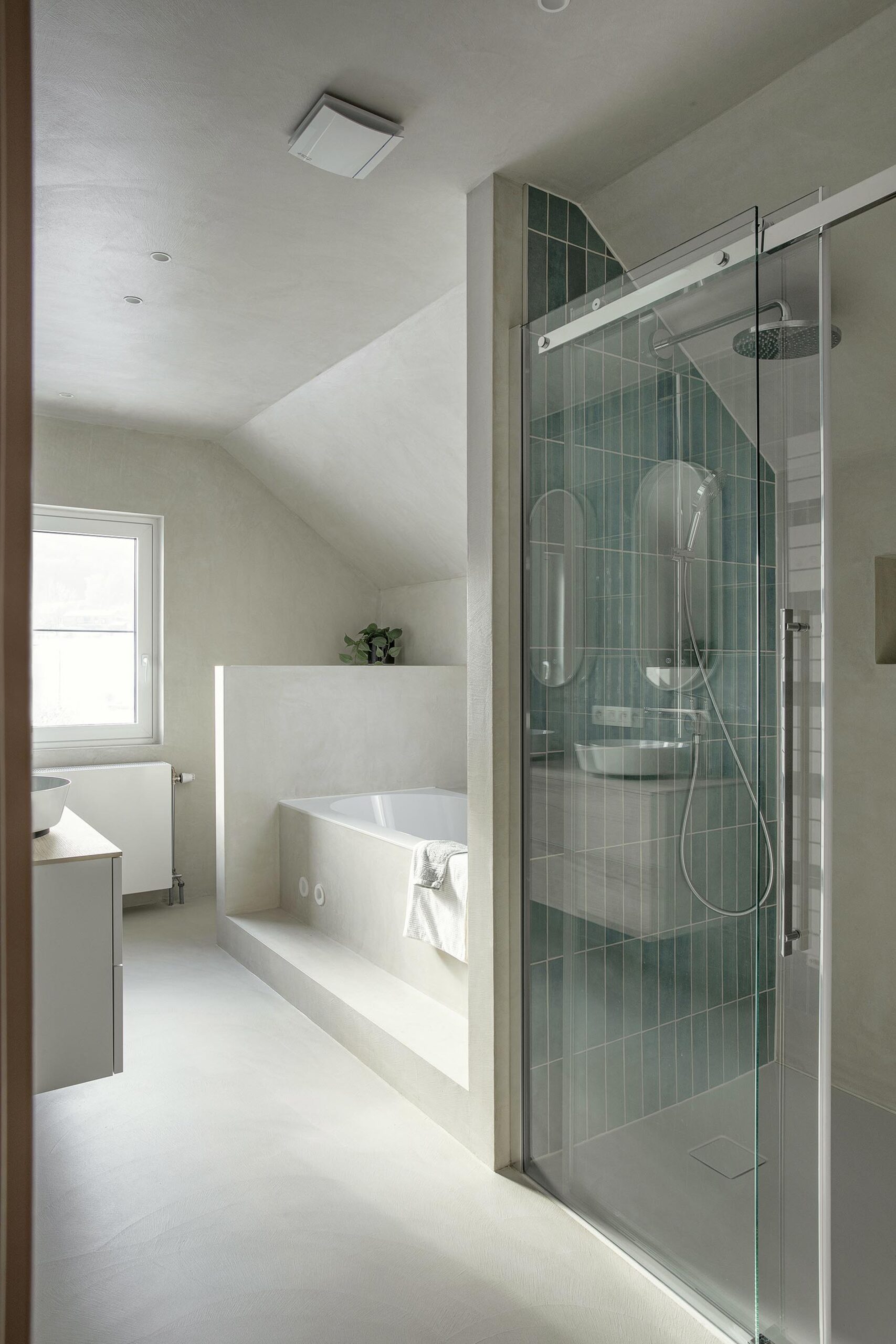 Salle de bains des enfants avec baignoire centrale, structure sur mesure en U et marche intégrée, dans une composition contemporaine, intime et élégante