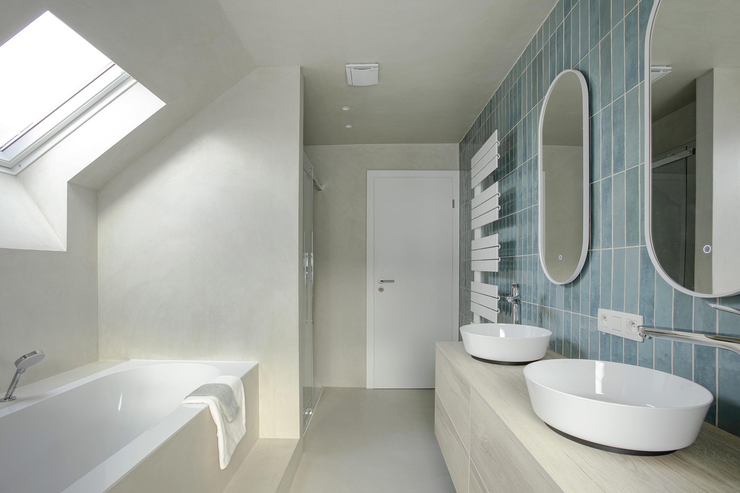 Salle de bains des enfants avec baignoire centrale, structure sur mesure en U et marche intégrée, dans une composition contemporaine, intime et élégante
