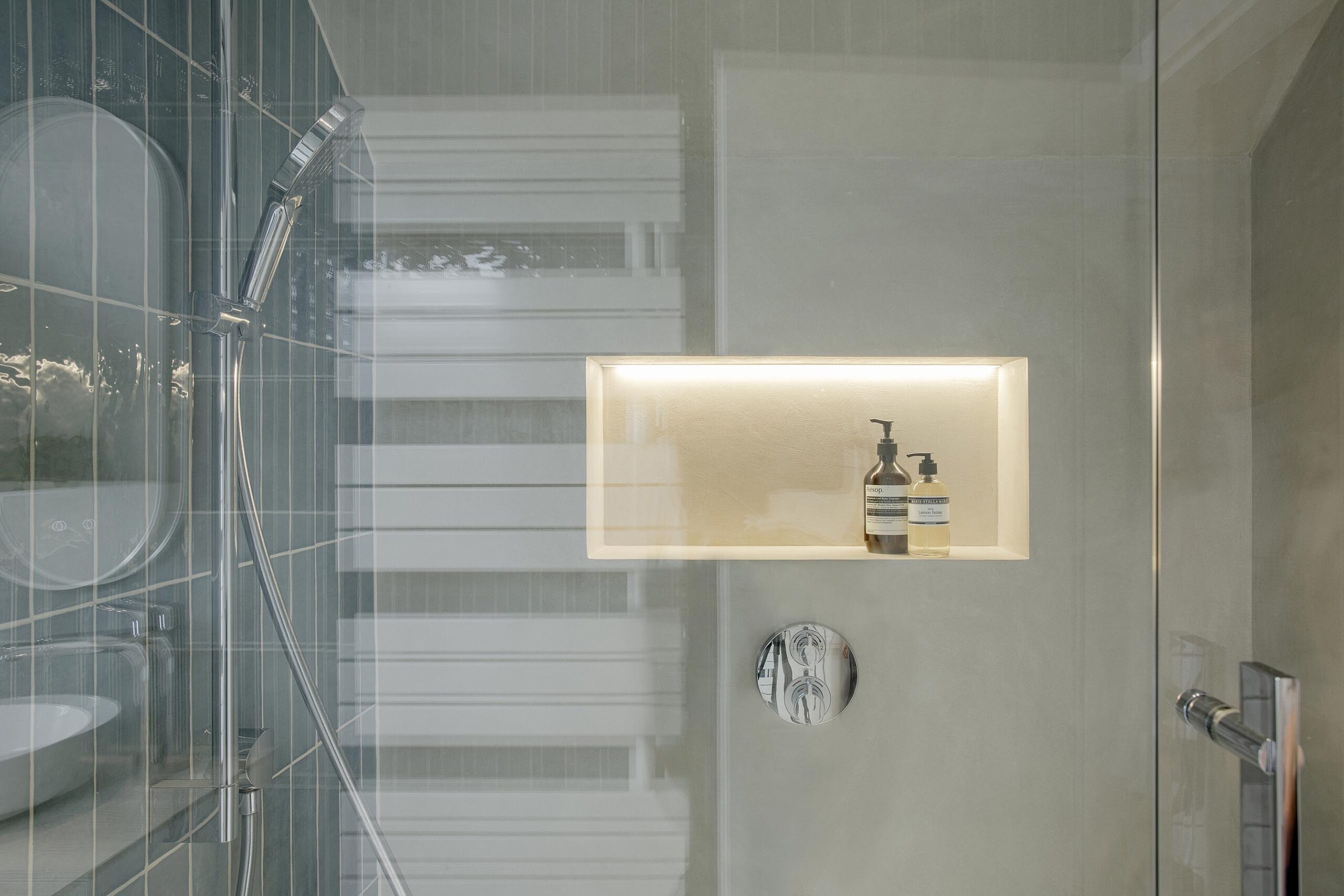 Salle de bains des enfants avec baignoire centrale, structure sur mesure en U et marche intégrée, dans une composition contemporaine, intime et élégante