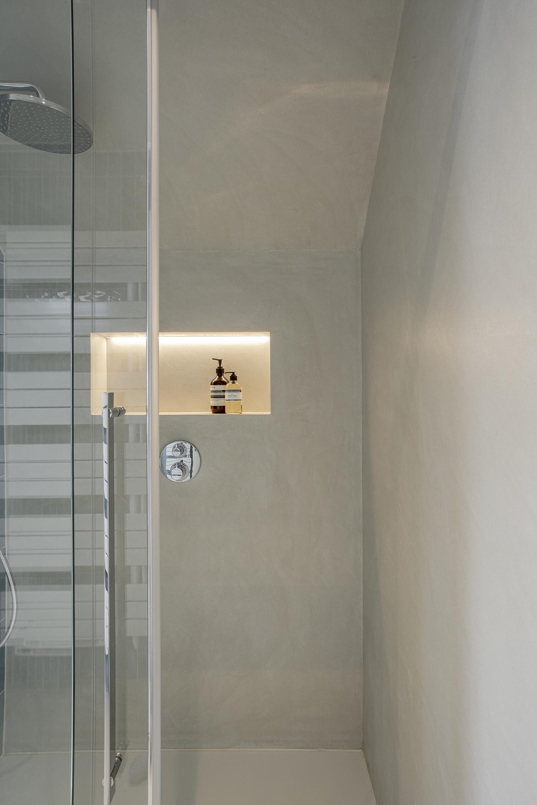 Salle de bains des enfants avec baignoire centrale, structure sur mesure en U et marche intégrée, dans une composition contemporaine, intime et élégante