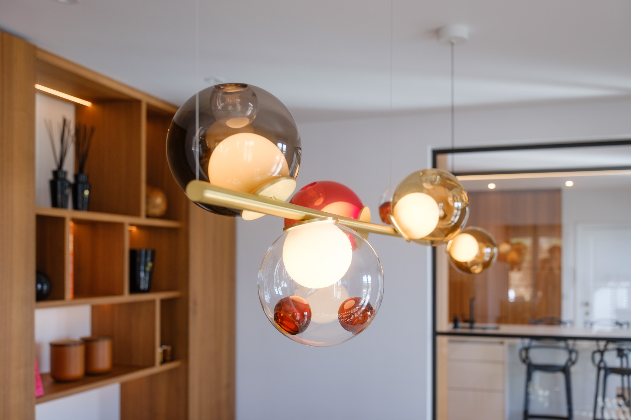 Salle à manger contemporaine avec mobilier sur mesure en noyer, table sculpturale et verrière ouvrant sur la cuisine.