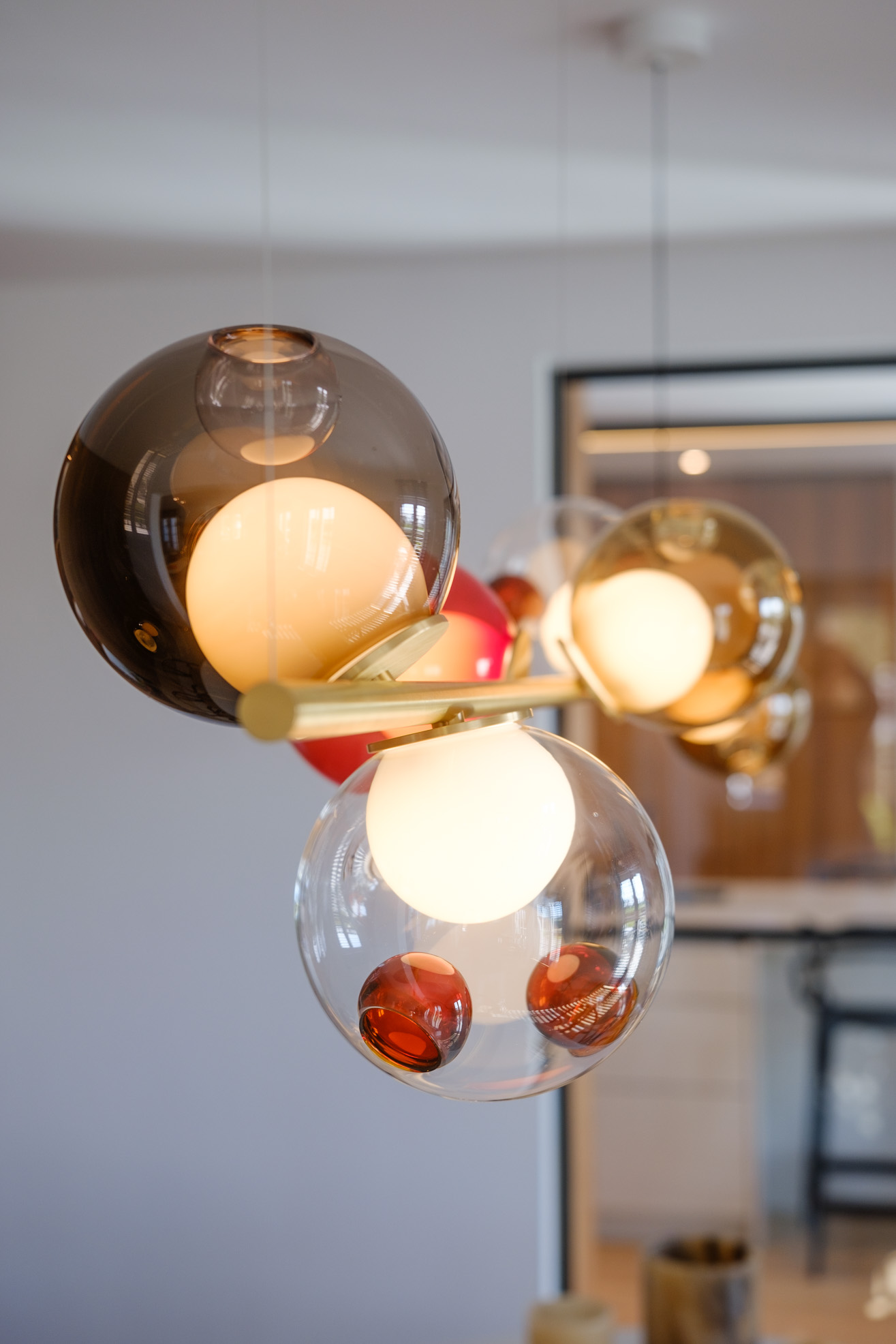 Salle à manger contemporaine avec mobilier sur mesure en noyer, table sculpturale et verrière ouvrant sur la cuisine.