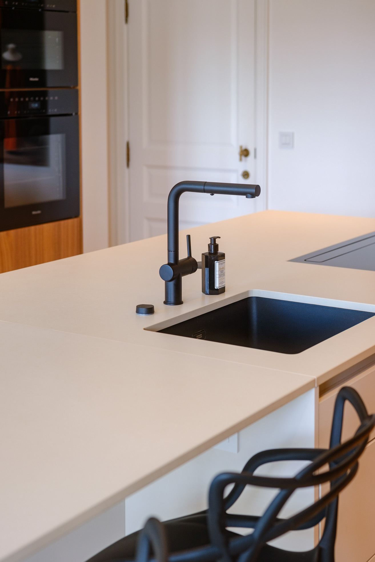 Salle à manger contemporaine avec mobilier sur mesure en noyer, table sculpturale et verrière ouvrant sur la cuisine.