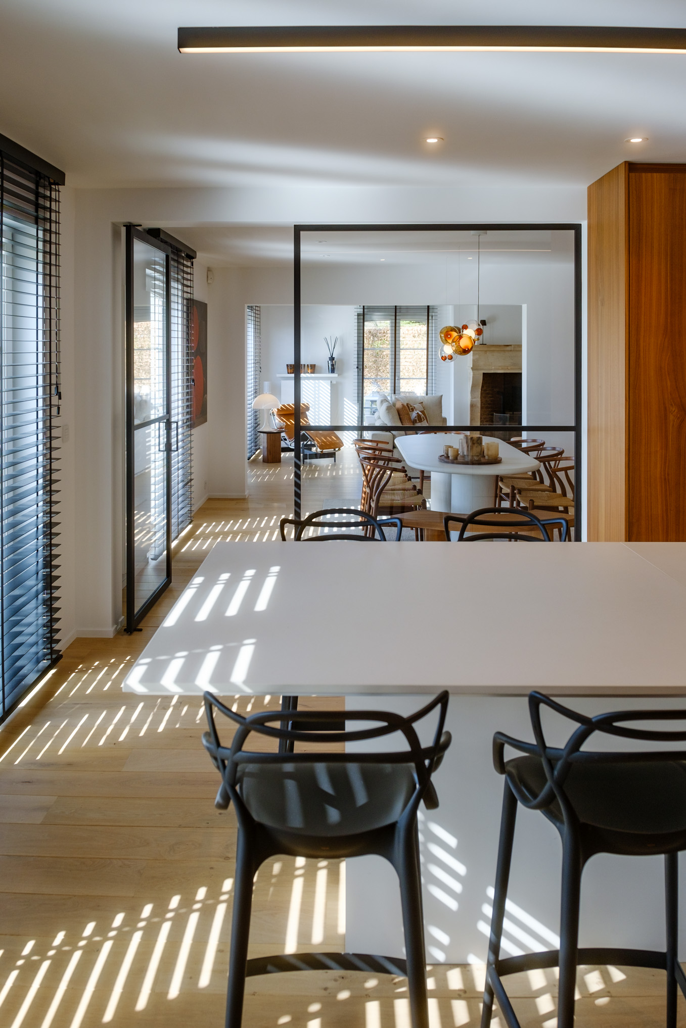 Salle à manger contemporaine avec mobilier sur mesure en noyer, table sculpturale et verrière ouvrant sur la cuisine