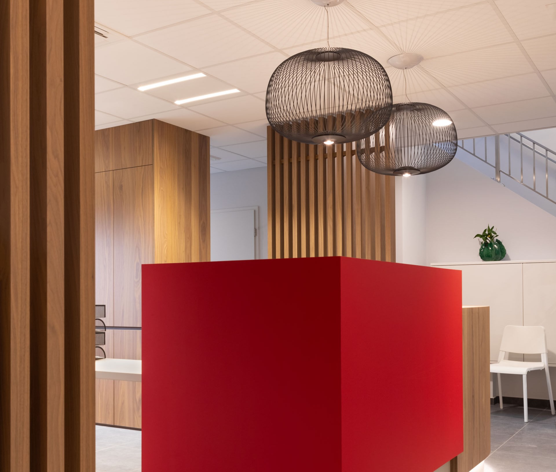Aménagement intérieur contemporain d’une étude notariale à Namur, avec mobilier en noyer, lignes courbes et accents rouge carmin dans une ambiance professionnelle haut de gamme