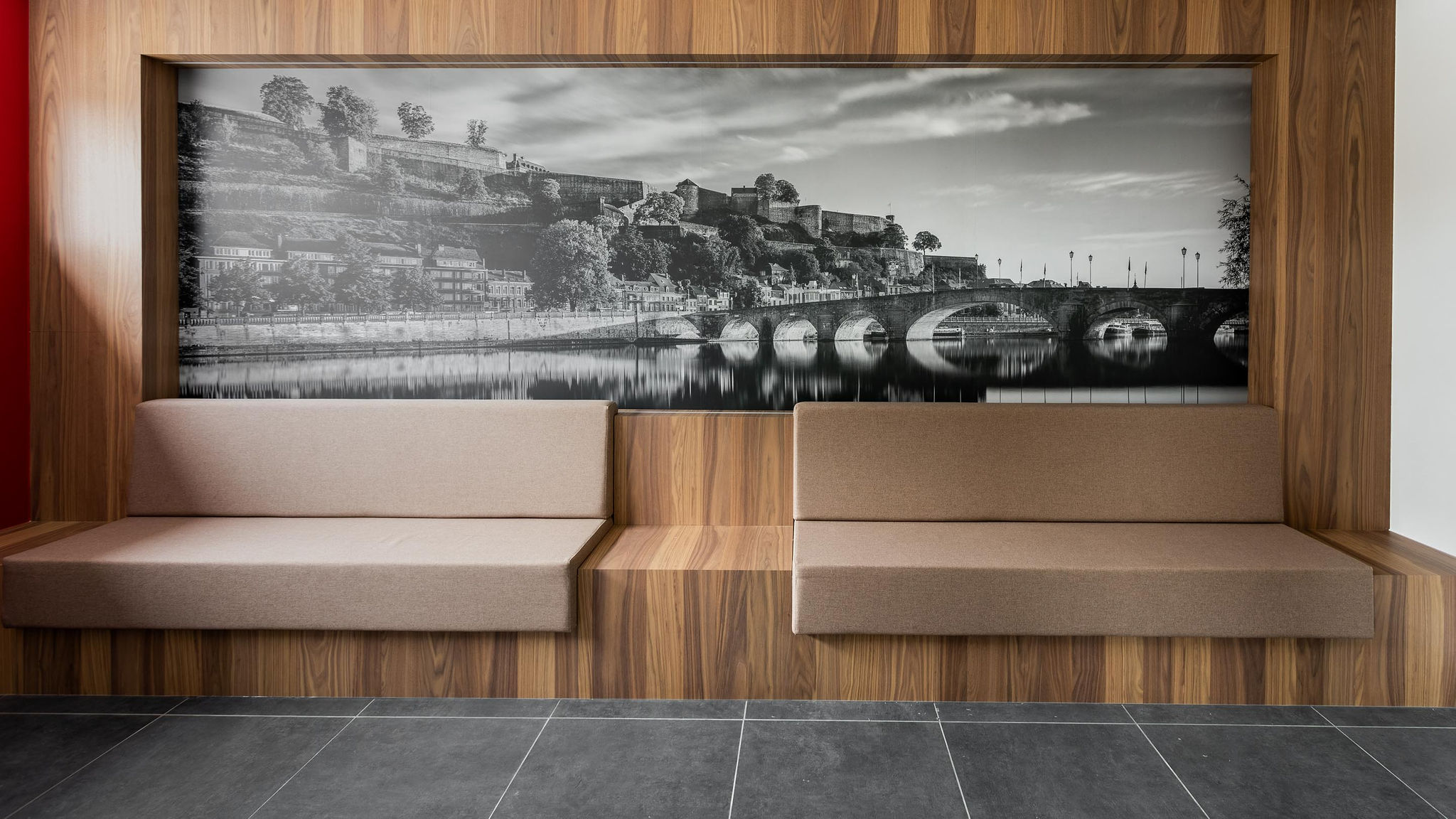 Aménagement intérieur contemporain d’une étude notariale à Namur, avec mobilier en noyer, lignes courbes et accents rouge carmin dans une ambiance professionnelle haut de gamme