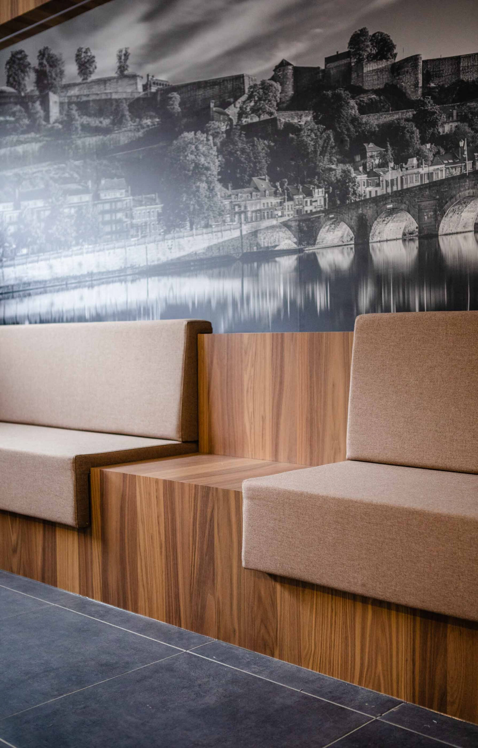 Aménagement intérieur contemporain d’une étude notariale à Namur, avec mobilier en noyer, lignes courbes et accents rouge carmin dans une ambiance professionnelle haut de gamme