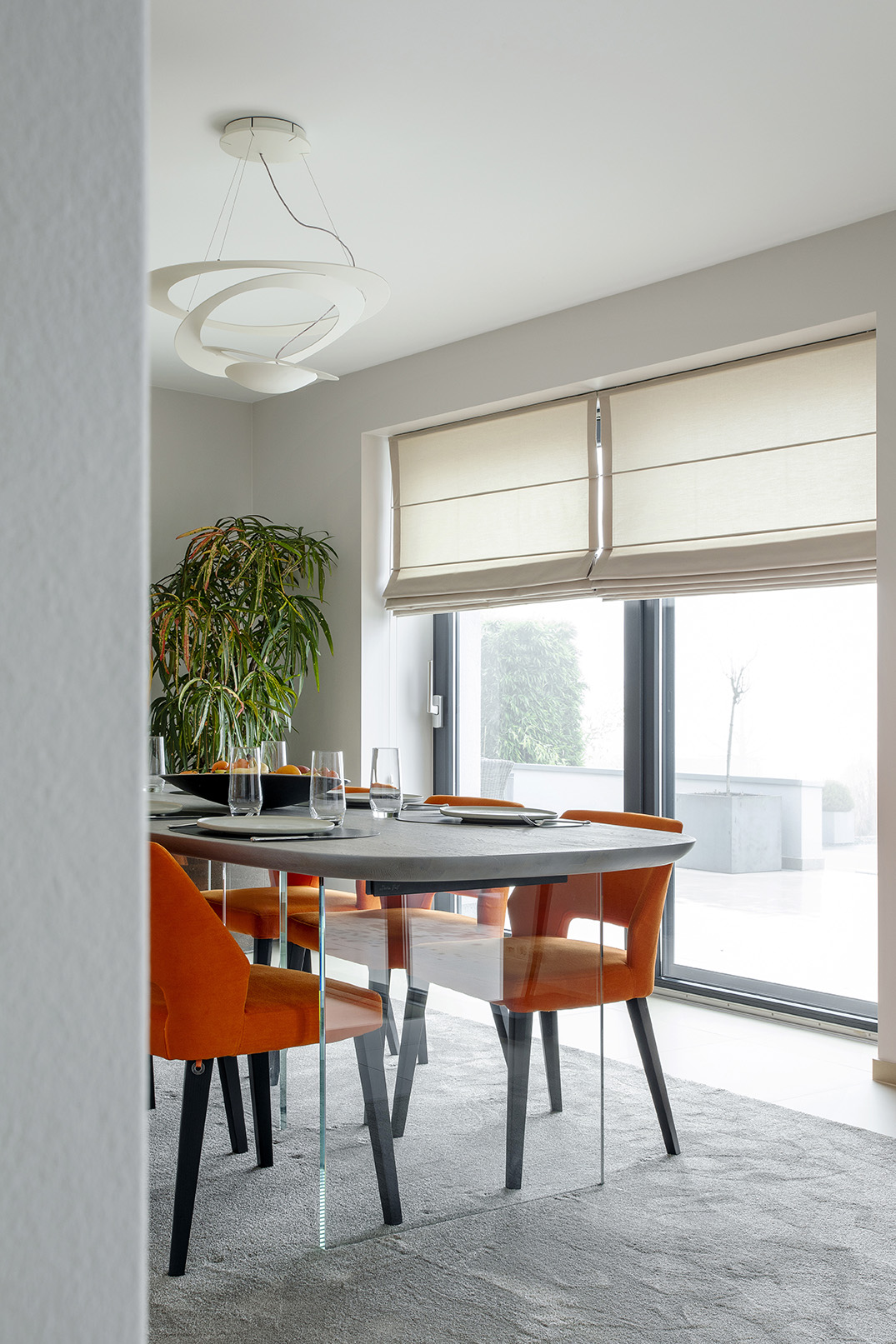 Salle à manger contemporaine ouverte sur le séjour, avec fauteuils orange, œuvres d’art et mobilier design, projet d’architecture d’intérieur à Arlon