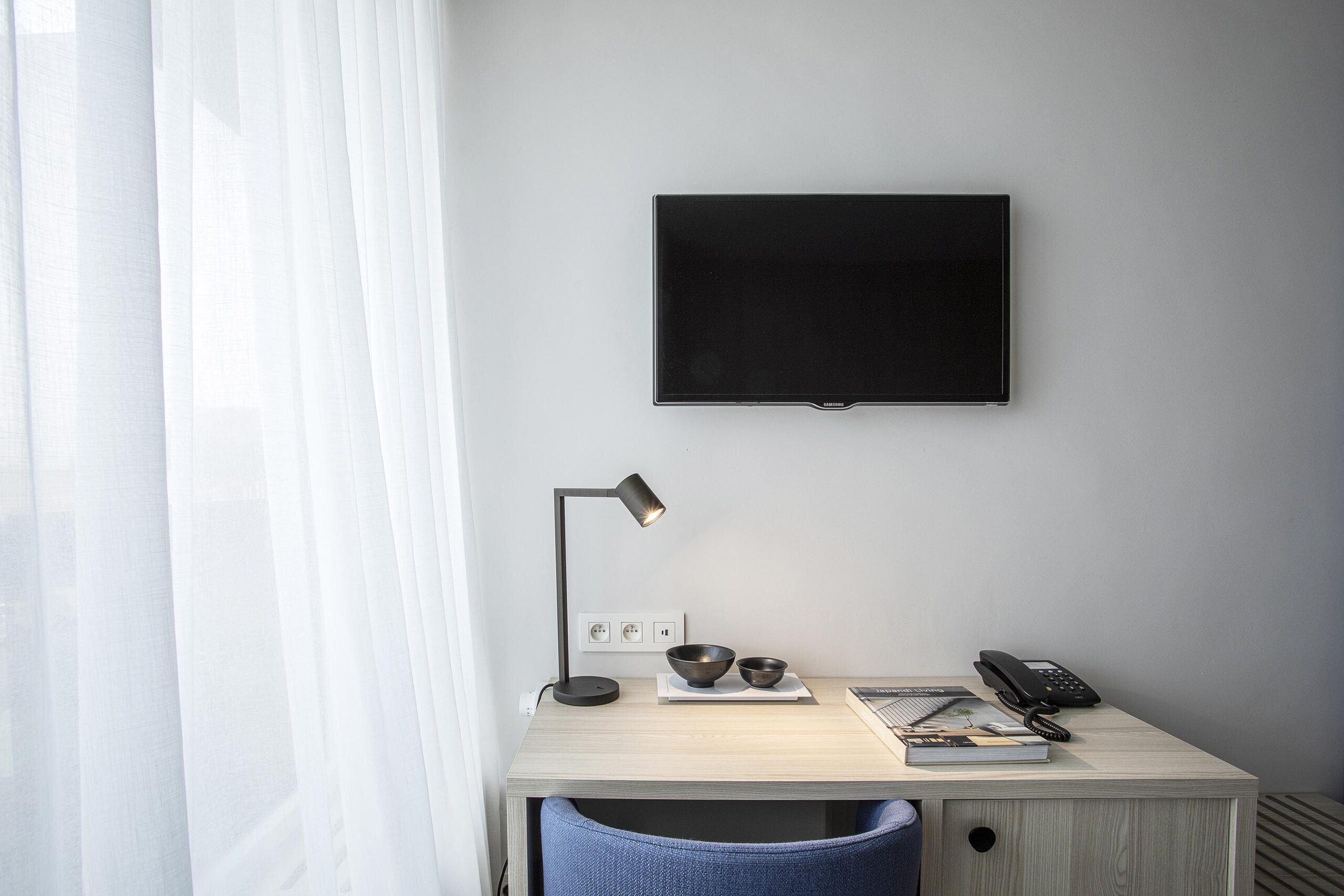Chambre d’hôtel contemporaine aux 3 Clés à Gembloux, avec tête de lit bleue sur mesure, habillage mural en bois clair et éclairage indirect chaleureux