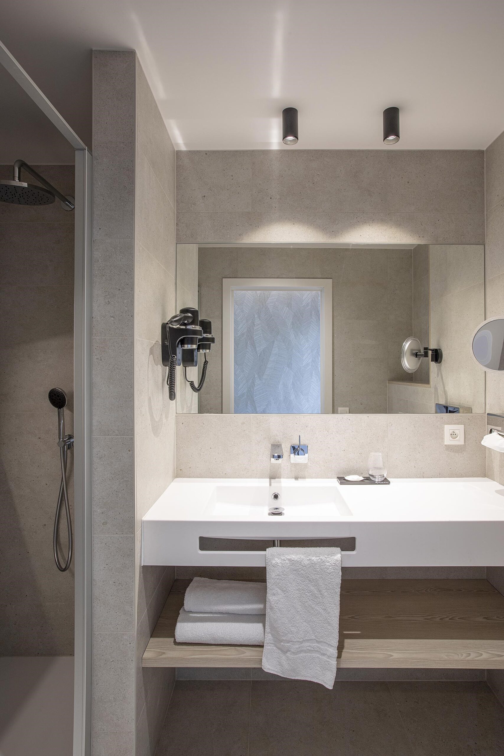 Chambre d’hôtel contemporaine aux 3 Clés à Gembloux, avec tête de lit bleue sur mesure, habillage mural en bois clair et éclairage indirect chaleureux