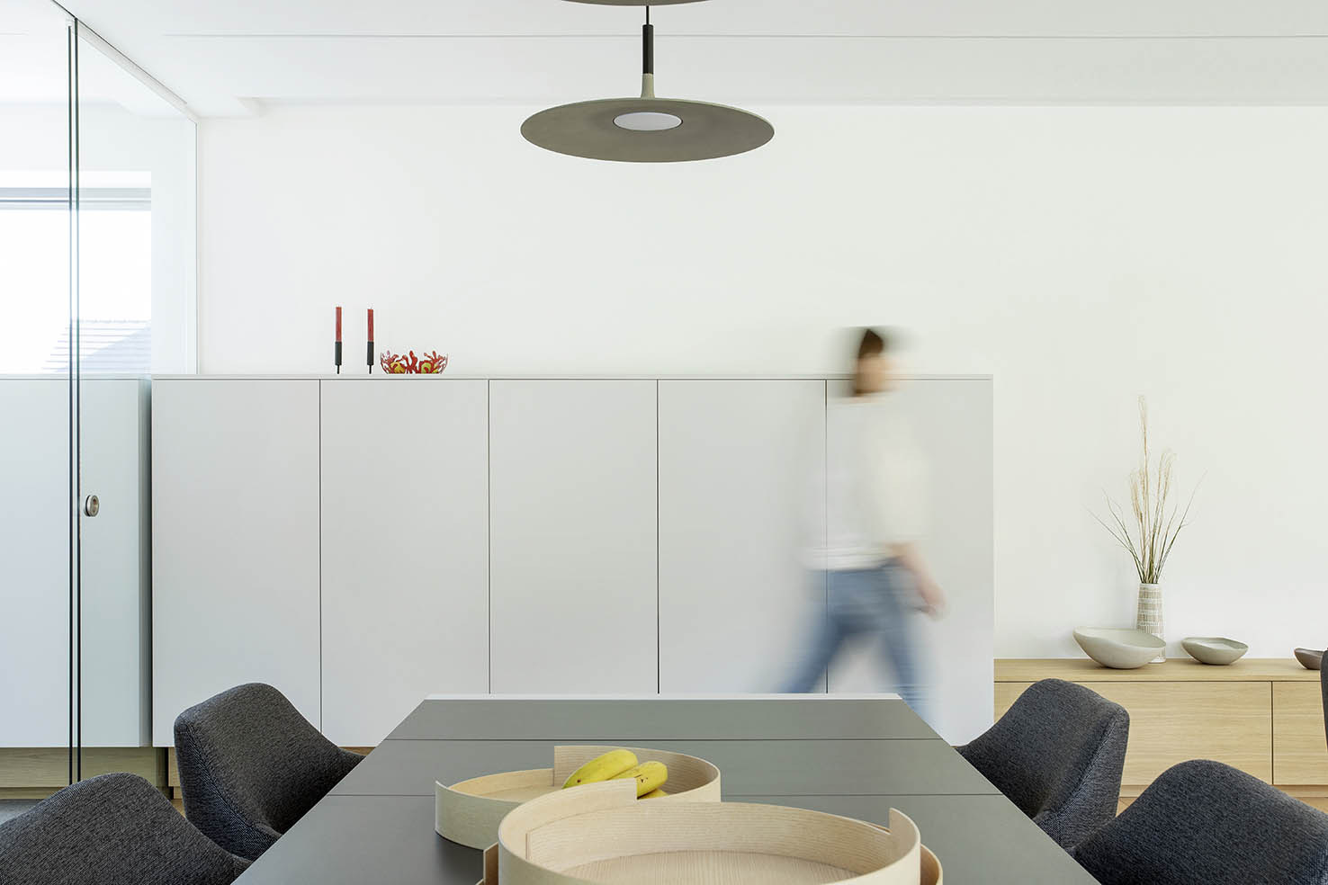 Hall d’entrée contemporain avec mobilier sur mesure en bois clair, banquette intégrée et paroi vitrée, projet d’architecture d’intérieur à Arlon.
