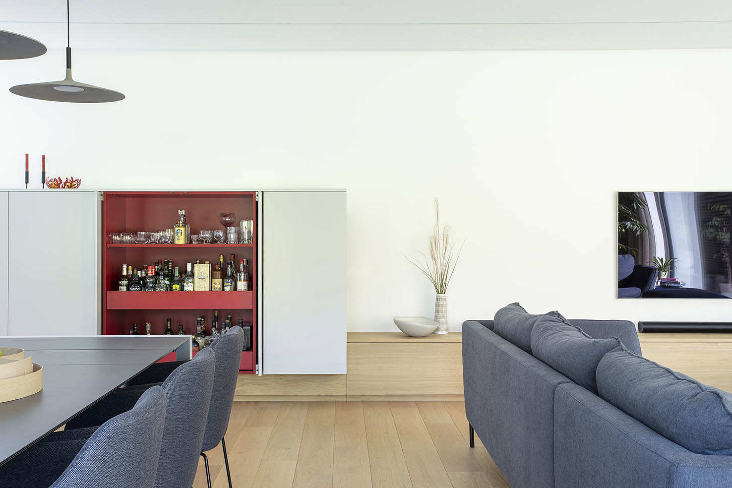 Hall d’entrée contemporain avec mobilier sur mesure en bois clair, banquette intégrée et paroi vitrée, projet d’architecture d’intérieur à Arlon.