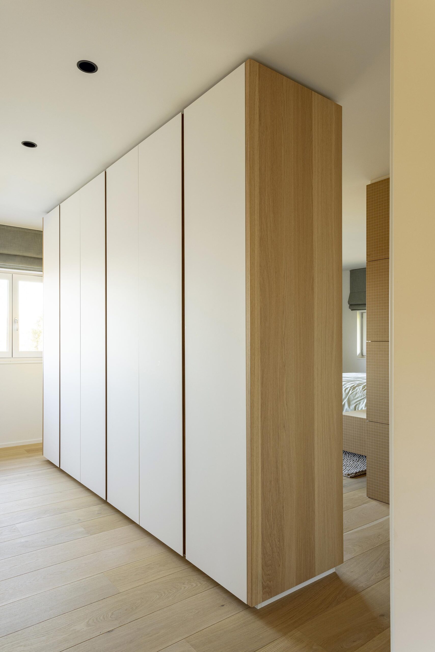 Chambre parentale contemporaine à Stavelot, avec parquet chaleureux, mobilier sur mesure, rangements intégrés et finitions raffinées dans une ambiance élégante et intimiste