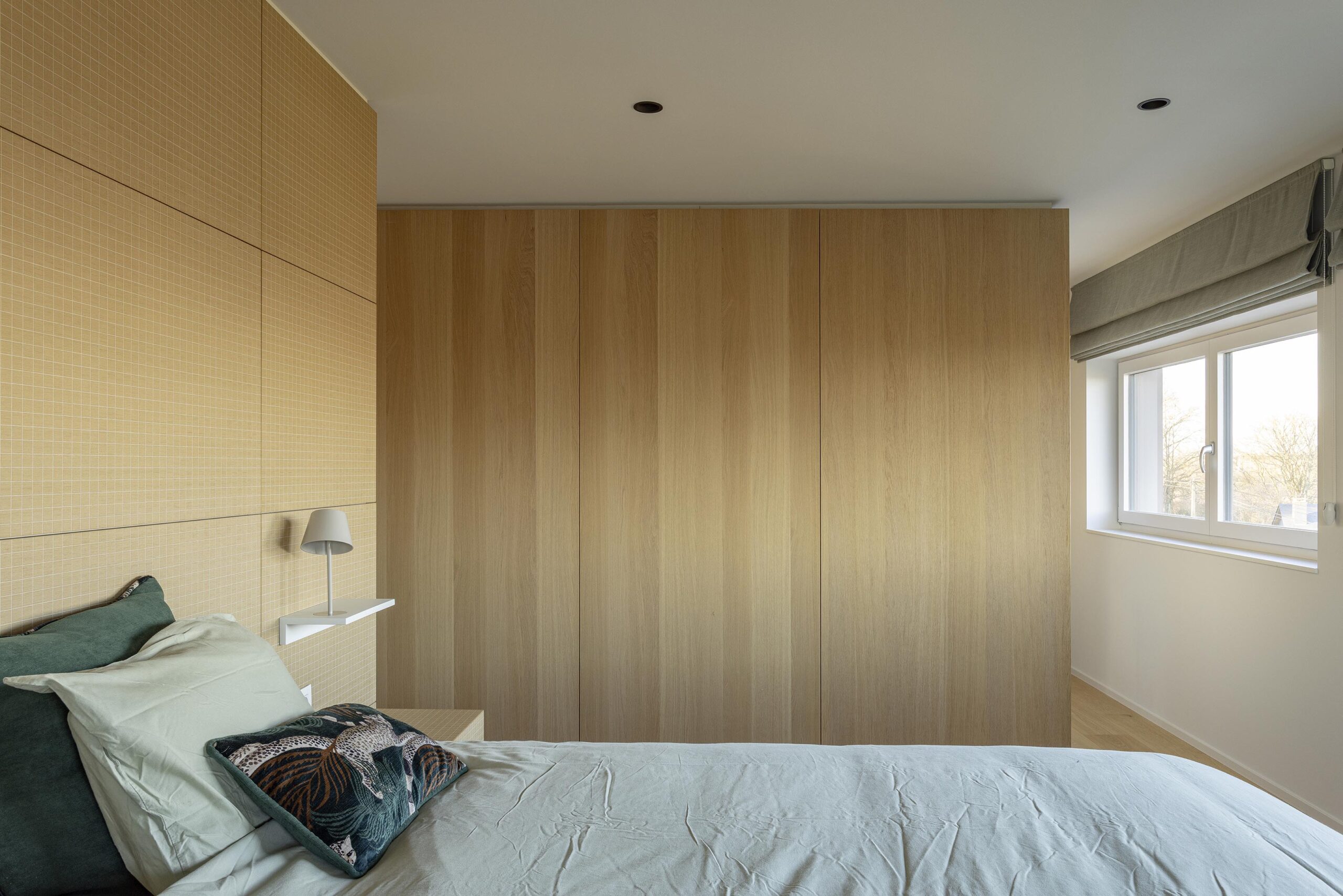 Chambre parentale contemporaine à Stavelot, avec parquet chaleureux, mobilier sur mesure, rangements intégrés et finitions raffinées dans une ambiance élégante et intimiste