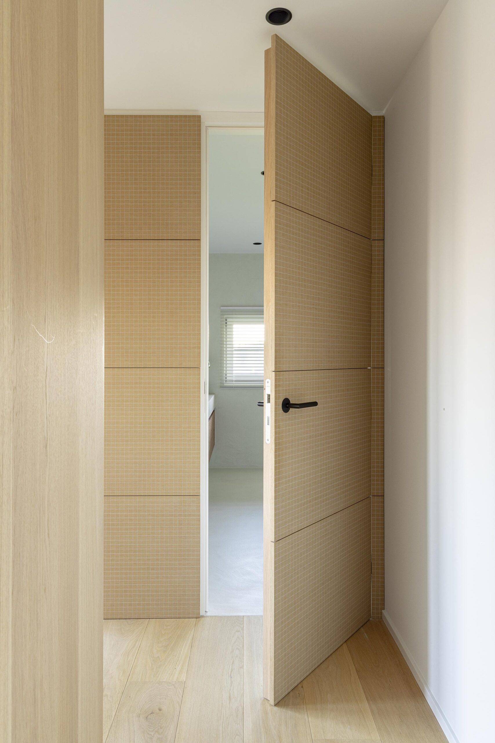 Chambre parentale contemporaine à Stavelot, avec parquet chaleureux, mobilier sur mesure, rangements intégrés et finitions raffinées dans une ambiance élégante et intimiste